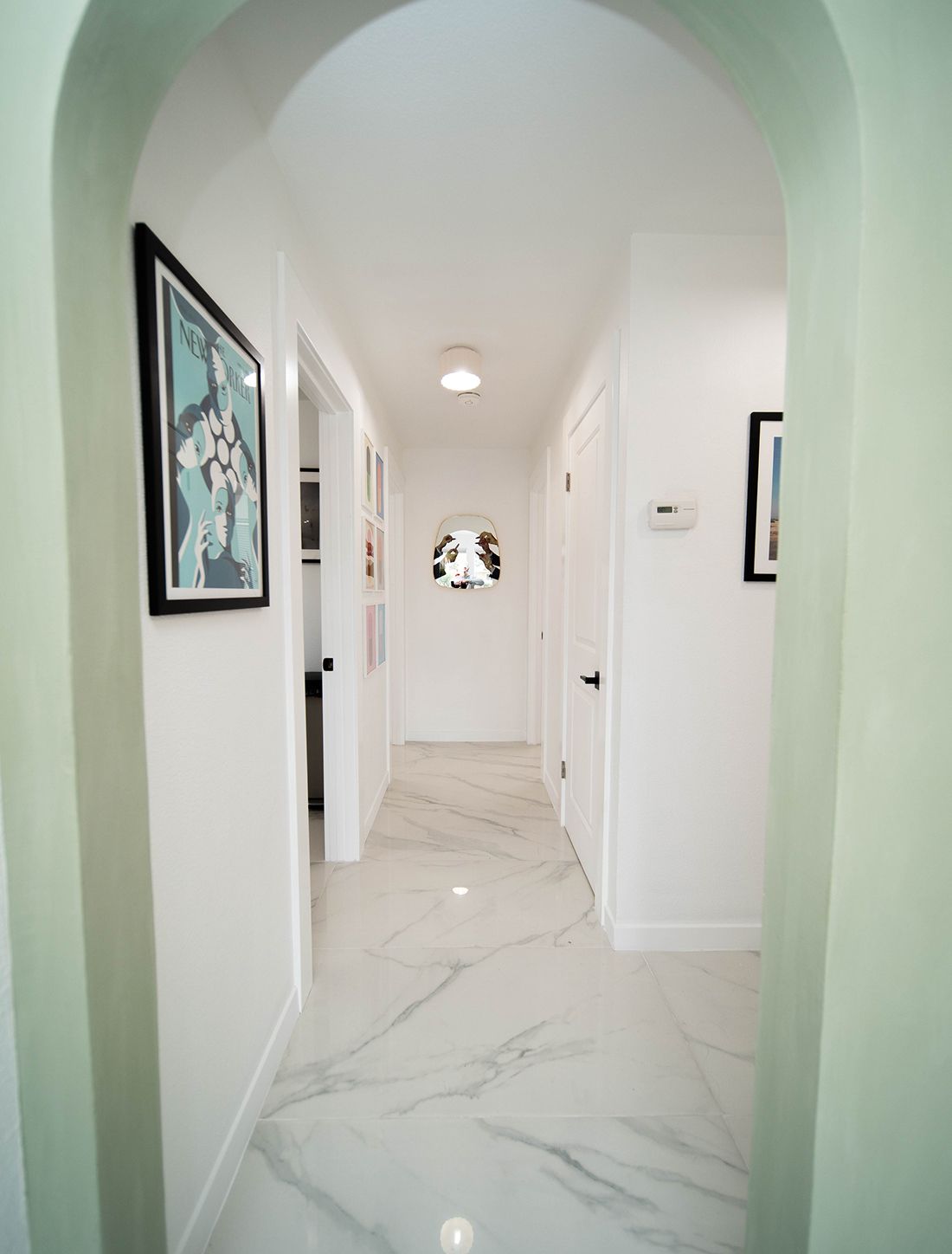 Modern hallway with marble floor and artwork.