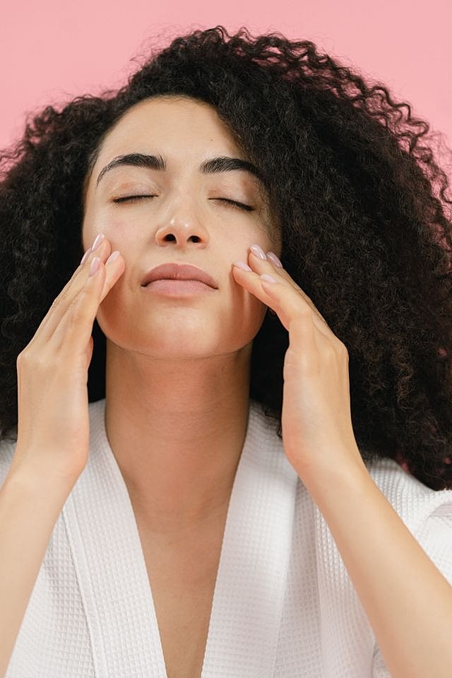Woman skincare routine with pink background.