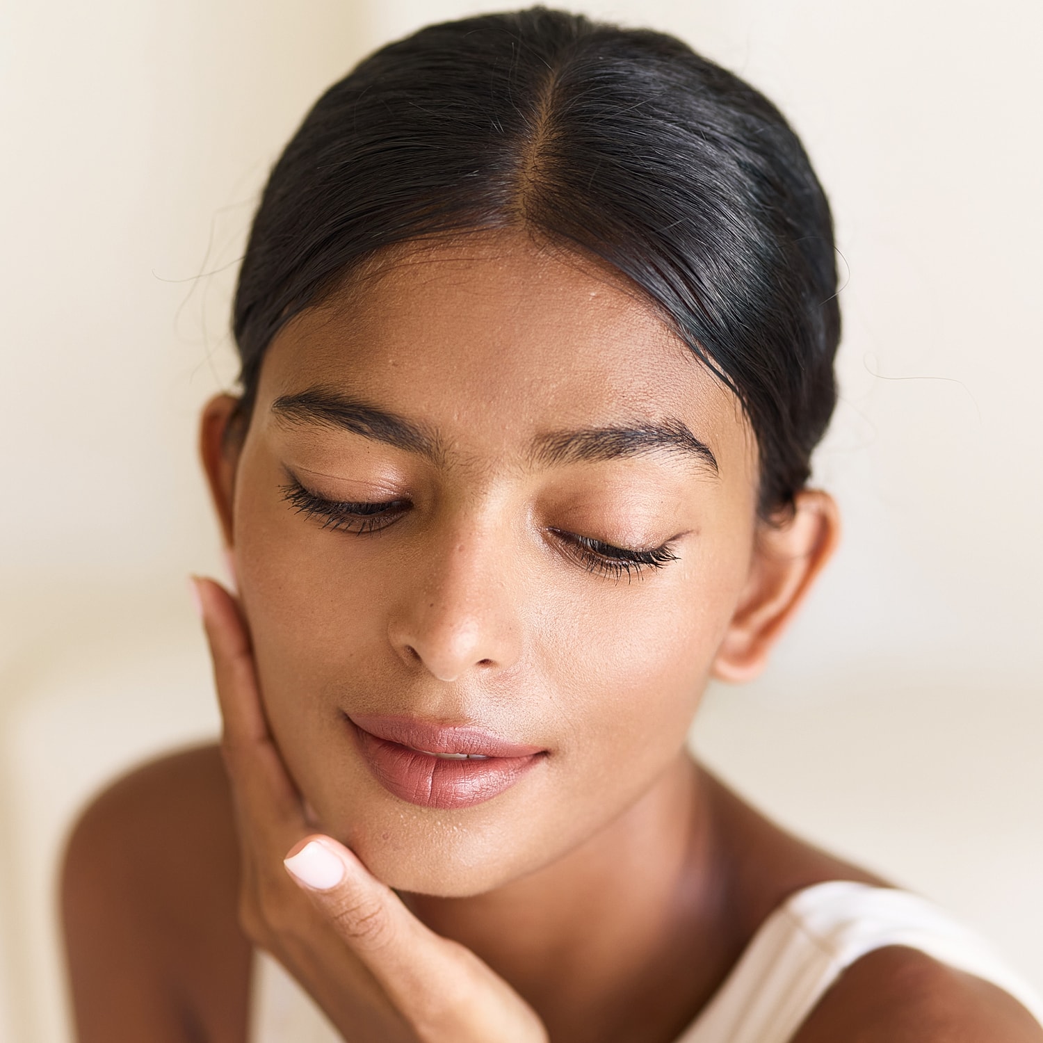 Woman gently touching her face, eyes closed.