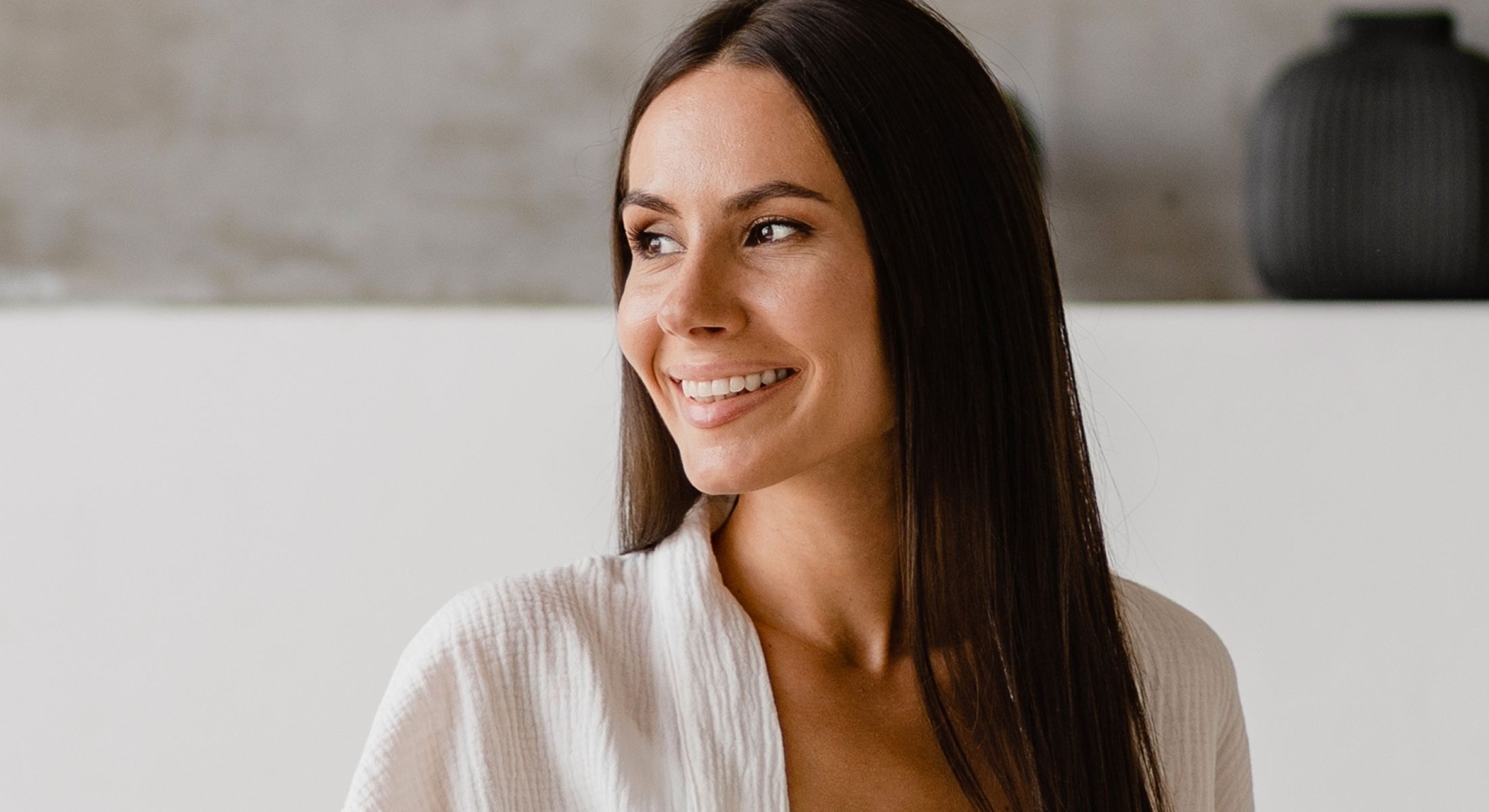Smiling woman with long hair and cozy outfit.